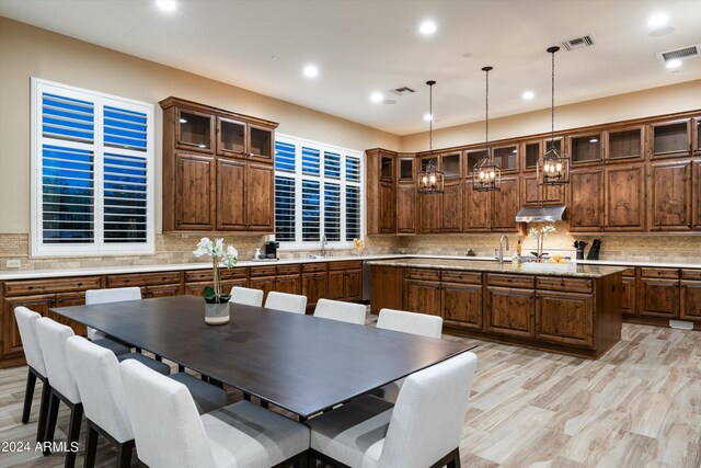 kitchen featuring light hardwood / wood-style flooring, decorative backsplash, and a kitchen island with sink