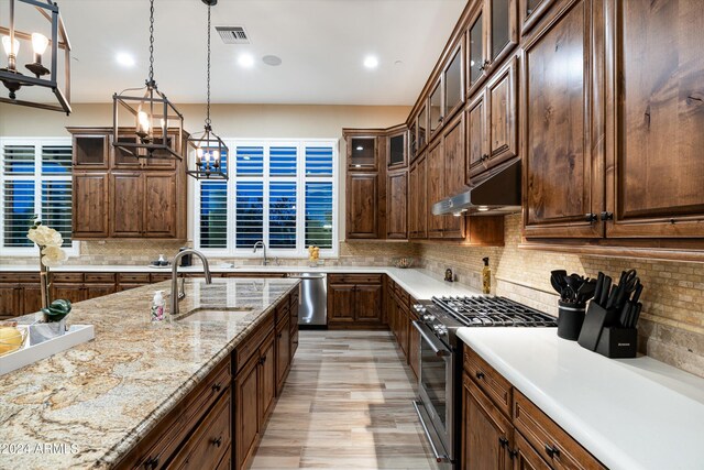 kitchen with pendant lighting, stainless steel appliances, decorative backsplash, and sink