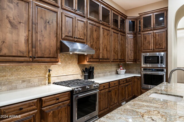 kitchen featuring stainless steel appliances, sink, backsplash, and dark brown cabinets