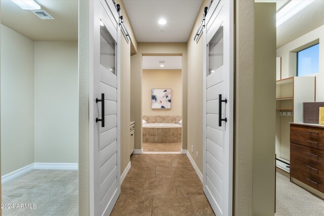 corridor featuring a barn door and carpet flooring