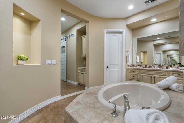 bathroom featuring vanity, tile patterned floors, and tiled bath