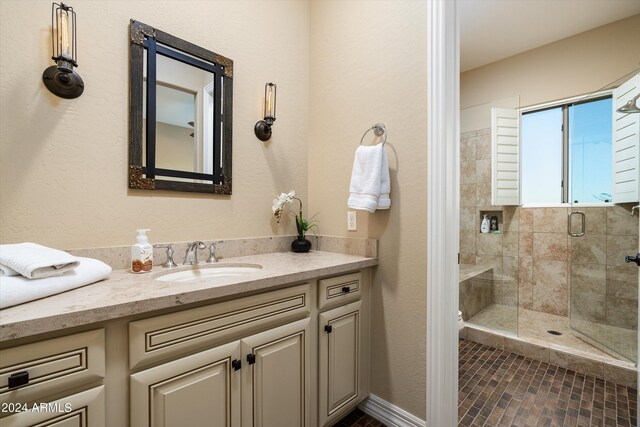 bathroom featuring a shower with door and vanity