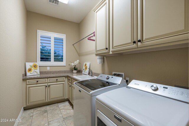 laundry room featuring washing machine and dryer, cabinets, sink, and light tile patterned floors