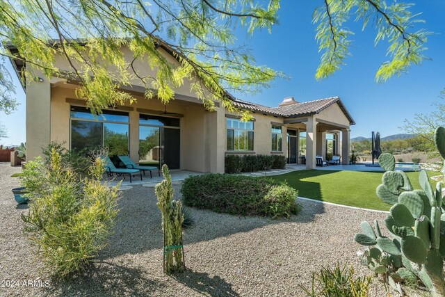 back of property with a lawn and a patio