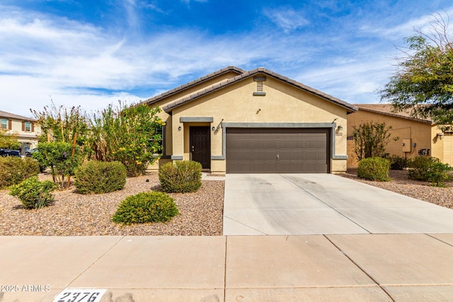 view of front of house featuring an attached garage, a tiled roof, concrete driveway, and stucco siding