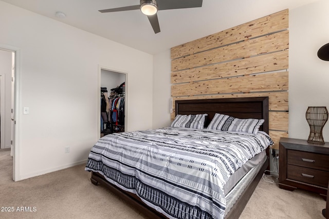 bedroom featuring carpet, a spacious closet, a ceiling fan, and a closet