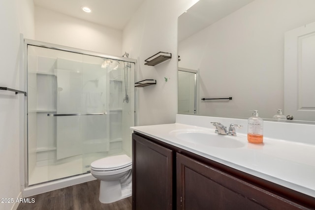 bathroom with a stall shower, toilet, wood finished floors, vanity, and recessed lighting