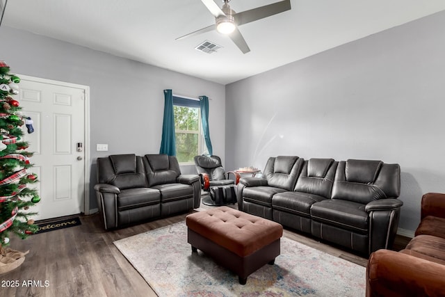 living room with a ceiling fan, visible vents, and wood finished floors