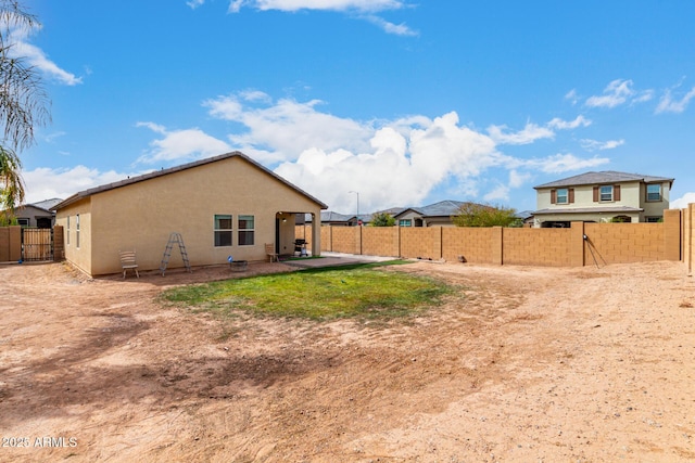 view of yard with a patio area, a fenced backyard, and a gate