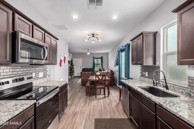 kitchen with visible vents, appliances with stainless steel finishes, open floor plan, dark brown cabinets, and a sink