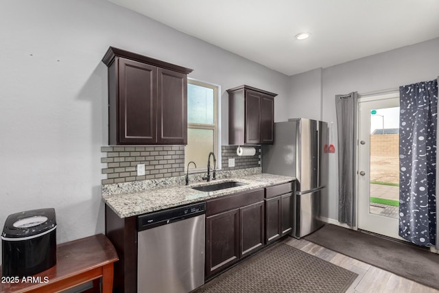 kitchen with tasteful backsplash, stainless steel appliances, dark brown cabinets, light wood-type flooring, and a sink