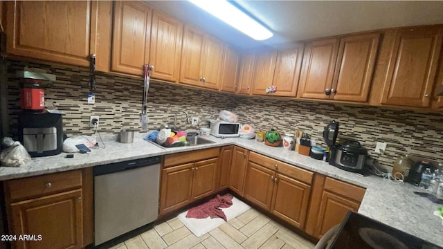 kitchen with dishwasher, light stone countertops, decorative backsplash, and sink