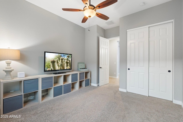 interior space with light carpet, baseboards, visible vents, ceiling fan, and a closet