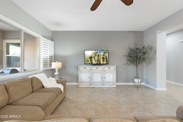 living area with light tile patterned flooring, a ceiling fan, and baseboards