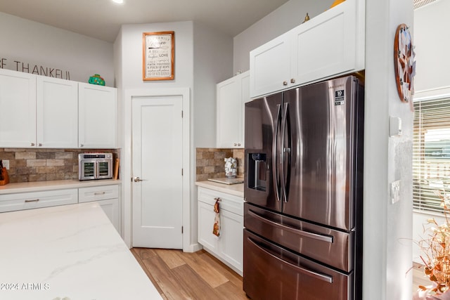 kitchen with white cabinets, stainless steel fridge, light hardwood / wood-style flooring, and light stone countertops