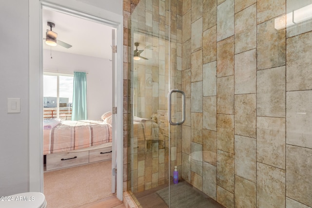 bathroom with a shower with door, toilet, and ceiling fan