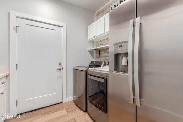 laundry area with cabinets, washing machine and dryer, and light hardwood / wood-style floors