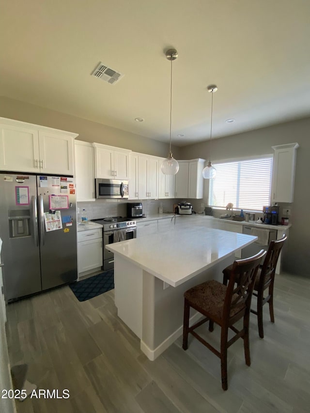 8026 S 6th Dr, Phoenix, AZ 85041 - kitchen with tasteful backsplash, visible vents, appliances with stainless steel finishes, wood finished floors, and light countertops
