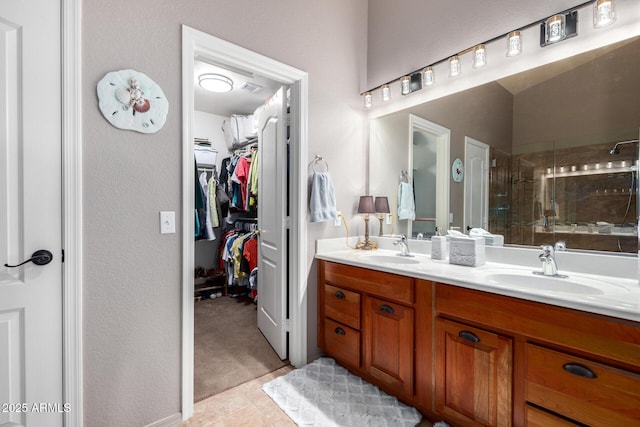 bathroom featuring a sink, double vanity, a shower stall, and a walk in closet