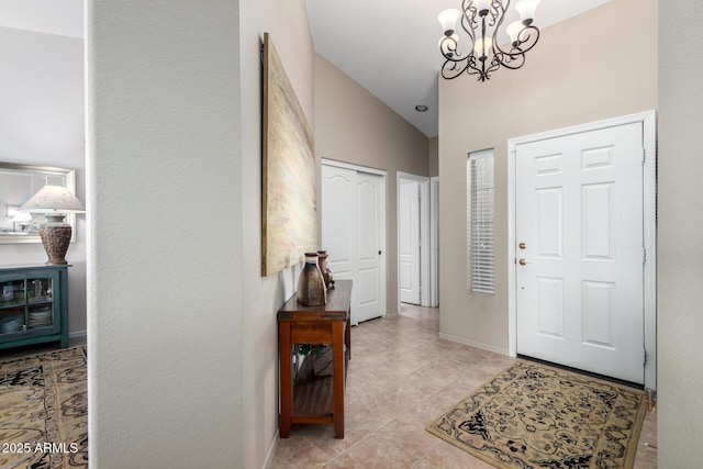 entryway with lofted ceiling, an inviting chandelier, and baseboards