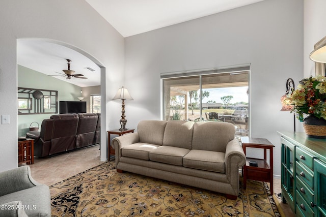 living area with lofted ceiling, ceiling fan, light tile patterned floors, arched walkways, and visible vents