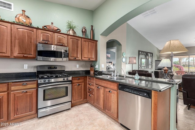 kitchen with visible vents, brown cabinets, open floor plan, a peninsula, and stainless steel appliances