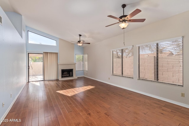 unfurnished living room featuring vaulted ceiling, a large fireplace, ceiling fan, and hardwood / wood-style floors