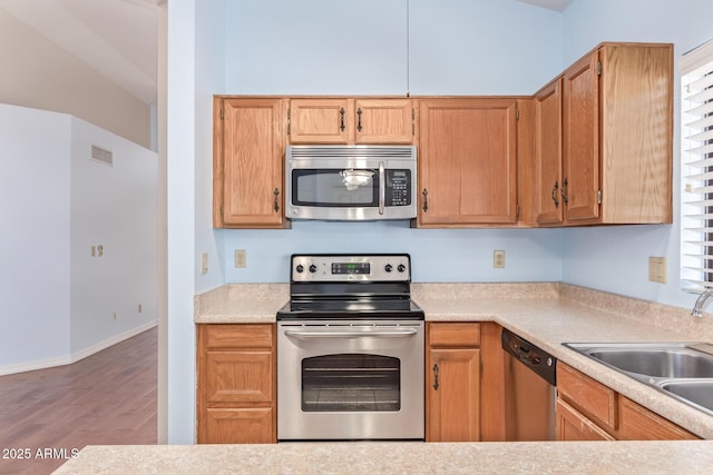 kitchen featuring stainless steel appliances, wood-type flooring, and sink