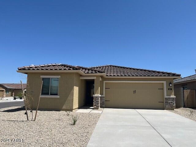 24606 W St Catherine Ave, Buckeye, AZ 85326 - view of front of house featuring a garage, concrete driveway, a tiled roof, and stucco siding