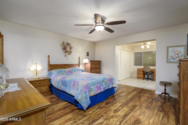 bedroom with ceiling fan, a textured ceiling, and wood finished floors