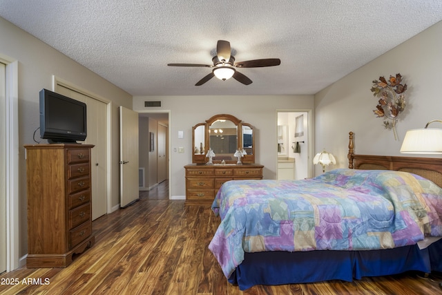 bedroom with dark wood-style floors, a textured ceiling, connected bathroom, and visible vents