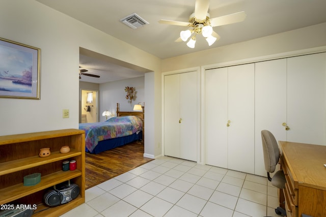 bedroom with a ceiling fan, visible vents, multiple closets, and light tile patterned flooring