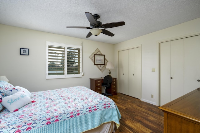 bedroom with a textured ceiling, wood finished floors, a ceiling fan, baseboards, and multiple closets