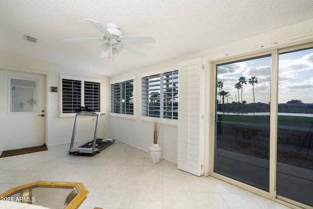 interior space with visible vents, a ceiling fan, vaulted ceiling, a textured ceiling, and tile patterned floors