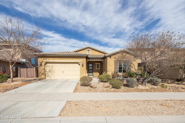 view of front facade featuring driveway, a garage, a tile roof, fence, and stucco siding