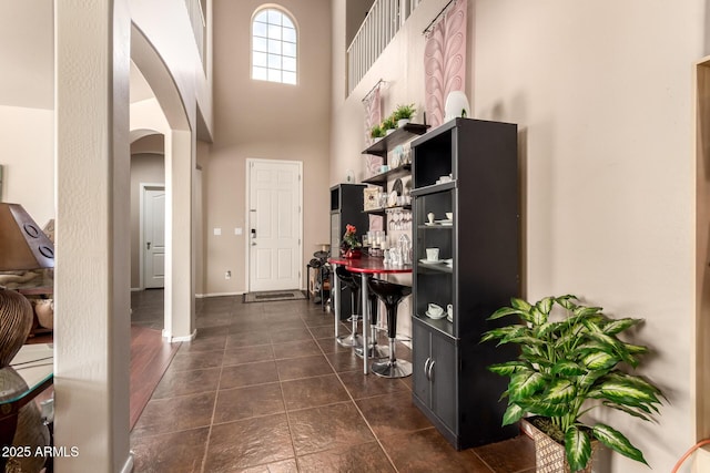 17153 W Gambit Trl, Surprise, AZ 85387 - foyer with arched walkways, a towering ceiling, and dark tile patterned flooring