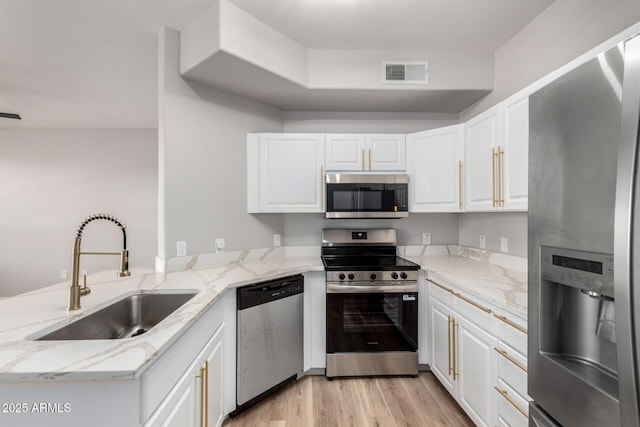 5303 N 7th St Unit 326, Phoenix, AZ 85014 - kitchen featuring appliances with stainless steel finishes, a peninsula, light stone countertops, and white cabinetry