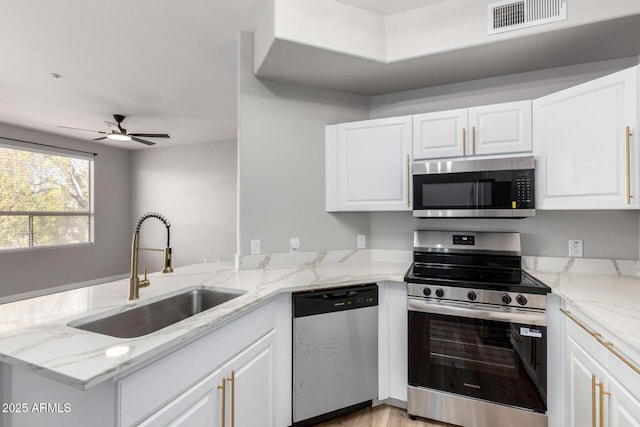 5303 N 7th St Unit 326, Phoenix, AZ 85014 - kitchen featuring appliances with stainless steel finishes, a peninsula, white cabinets, and light stone countertops