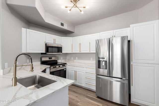 5303 N 7th St Unit 326, Phoenix, AZ 85014 - kitchen featuring stainless steel appliances, light stone countertops, white cabinets, a chandelier, and light wood-type flooring