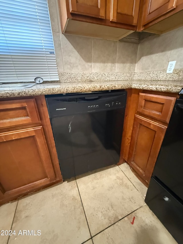 kitchen with light stone countertops, backsplash, light tile patterned flooring, and black appliances