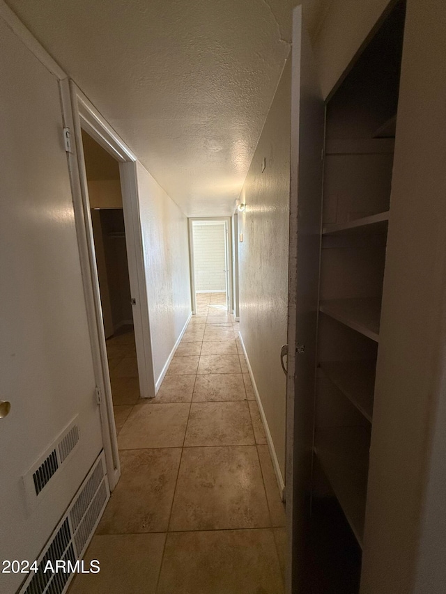 corridor with light tile patterned floors and a textured ceiling