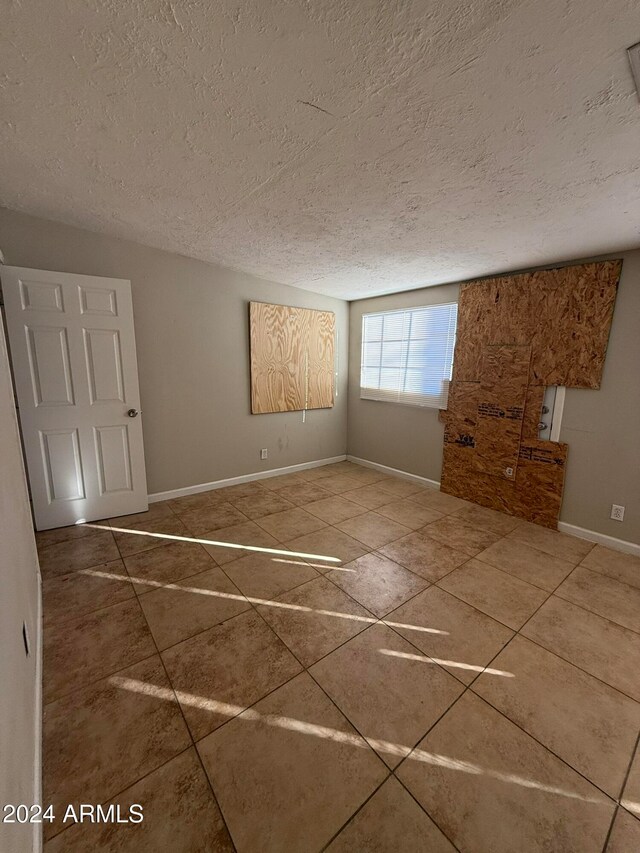 unfurnished room with tile patterned floors and a textured ceiling