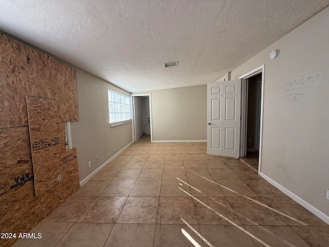 unfurnished room featuring light tile patterned flooring and a textured ceiling