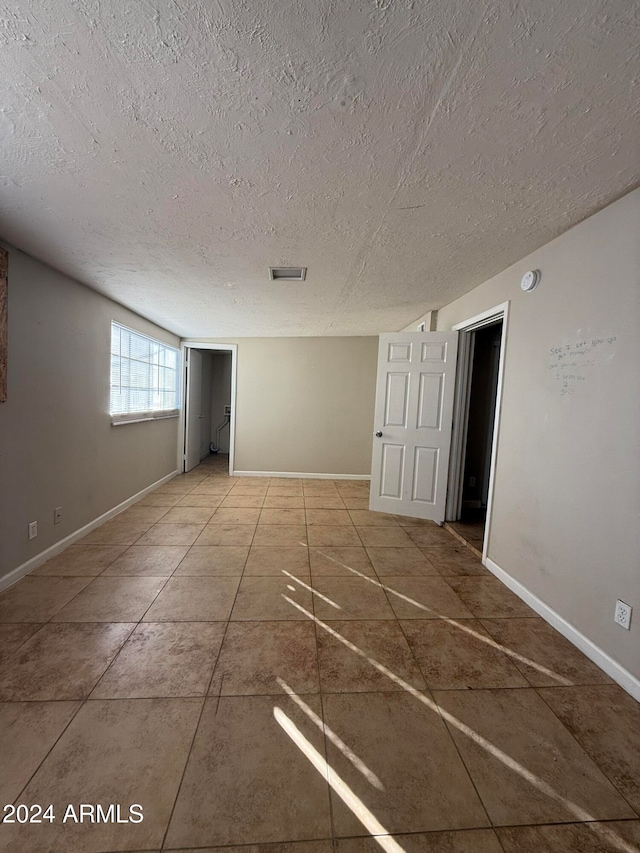 unfurnished room with tile patterned flooring and a textured ceiling