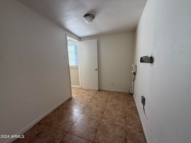 hall featuring a textured ceiling and light tile patterned flooring