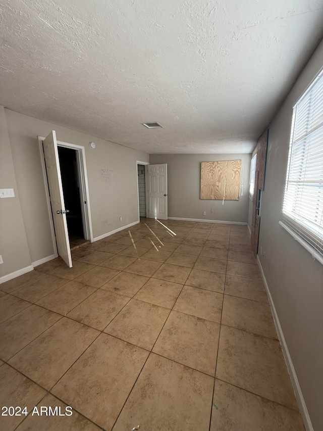 tiled empty room with a textured ceiling