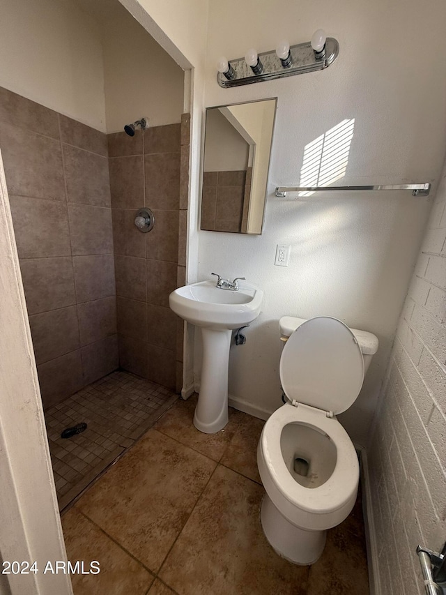 bathroom with a tile shower, tile patterned floors, sink, and toilet