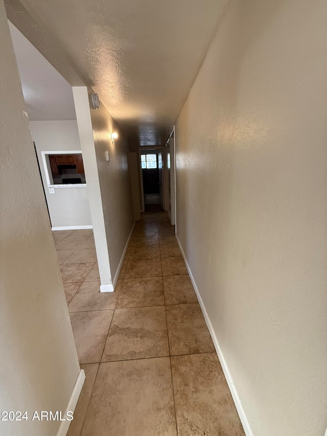 hall with tile patterned flooring and a textured ceiling