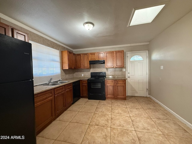 kitchen featuring a skylight, sink, a textured ceiling, decorative backsplash, and black appliances