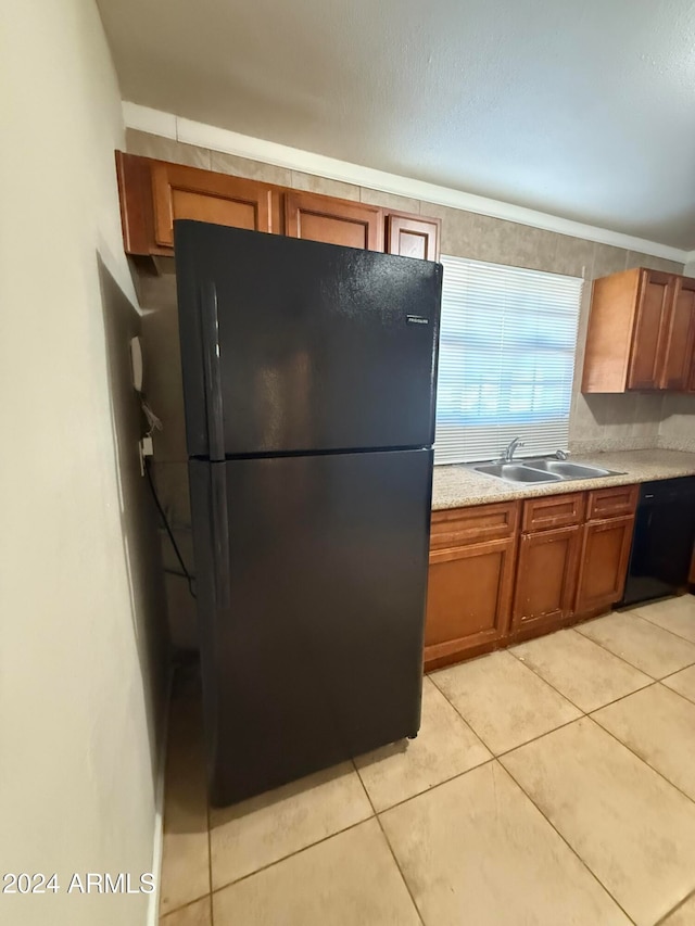 kitchen featuring sink, light tile patterned flooring, and black appliances